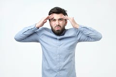 Ο νεαρός άνδρας με τη σκοτεινές τρίχα και τη γενειάδα φορά το μπλε πουκάμισο φαίνεται 0, χείλια που ζαρώνονται συνοφρύωμα brows στοκ φωτογραφίες με δικαίωμα ελεύθερης χρήσης Ο νεαρός άνδρας με τη σκοτεινές τρίχα και τη γενειάδα φορά το μπλε πουκάμισο φαίνεται 0, χείλια που ζαρώνονται συνοφρύωμα brows στοκ φωτογραφίες με δικαίωμα ελεύθερης χρήσης