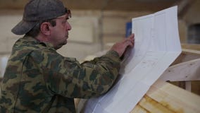 Ο ξυλουργός μελετά το σχέδιο της βάρκας στο ναυπηγείο απόθεμα βίντεο Ο ξυλουργός μελετά το σχέδιο της βάρκας στο ναυπηγείο απόθεμα βίντεο