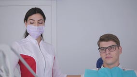 Ο οδοντίατρος ανοίγει το λαμπτήρα και κατευθύνει το φως στη συνεδρίαση ατόμων στην οδοντική καρέκλα απόθεμα βίντεο Ο οδοντίατρος ανοίγει το λαμπτήρα και κατευθύνει το φως στη συνεδρίαση ατόμων στην οδοντική καρέκλα απόθεμα βίντεο