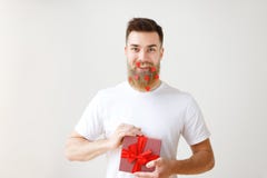 Ο οριζόντιος πυροβολισμός του εύθυμου γενειοφόρου αρσενικού με το καθιερώνον τη μόδα hairdo, κρατά το κιβώτιο δώρων, προετοιμάζει στοκ φωτογραφία με δικαίωμα ελεύθερης χρήσης Ο οριζόντιος πυροβολισμός του εύθυμου γενειοφόρου αρσενικού με το καθιερώνον τη μόδα hairdo, κρατά το κιβώτιο δώρων, προετοιμάζει στοκ φωτογραφία με δικαίωμα ελεύθερης χρήσης