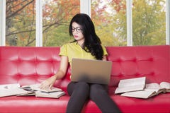 Ο φοιτητής πανεπιστημίου με το lap-top διαβάζει τα βιβλία στον καναπέ στοκ εικόνες Ο φοιτητής πανεπιστημίου με το lap-top διαβάζει τα βιβλία στον καναπέ στοκ εικόνες