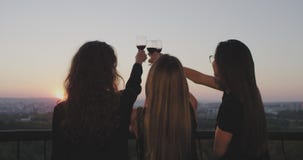 Ο χρόνος τρία ηλιοβασιλέματος κυρίες στο μπαλκόνι στην κορυφή της οικοδόμησης θαυμάζει το ηλιοβασίλεμα όλα μαζί και πίνοντας ένα απόθεμα βίντεο Ο χρόνος τρία ηλιοβασιλέματος κυρίες στο μπαλκόνι στην κορυφή της οικοδόμησης θαυμάζει το ηλιοβασίλεμα όλα μαζί και πίνοντας ένα απόθεμα βίντεο