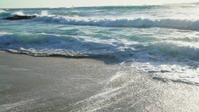 Ο ωκεανός είναι βαθιά μπλε, τα κύματα πλένονται από την αμμώδη παραλία της θερινής ακτής, οι ακτίνες του ήλιου απόθεμα βίντεο Ο ωκεανός είναι βαθιά μπλε, τα κύματα πλένονται από την αμμώδη παραλία της θερινής ακτής, οι ακτίνες του ήλιου απόθεμα βίντεο