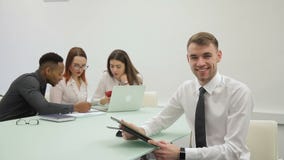 Ο όμορφος επιχειρηματίας χαμογελά διαβάζοντας την έκθεση σχετικά με την ταμπλέτα του στο ομο-εργαζόμενο δωμάτιο φιλμ μικρού μήκους Ο όμορφος επιχειρηματίας χαμογελά διαβάζοντας την έκθεση σχετικά με την ταμπλέτα του στο ομο-εργαζόμενο δωμάτιο φιλμ μικρού μήκους