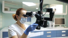 Οδοντίατρος που χρησιμοποιεί το οδοντικό μικροσκόπιο στην οδοντιατρική φιλμ μικρού μήκους Οδοντίατρος που χρησιμοποιεί το οδοντικό μικροσκόπιο στην οδοντιατρική φιλμ μικρού μήκους