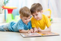 Οι αδελφοί παιδιών διαβάζουν ένα βιβλίο στο σπίτι στοκ εικόνες Οι αδελφοί παιδιών διαβάζουν ένα βιβλίο στο σπίτι στοκ εικόνες