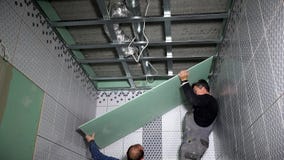 Οι ερασιτεχνικοί εργαζόμενοι εγκαθιστούν τον πίνακα ξηρών τοίχων γύψου στο ανώτατο όριο φιλμ μικρού μήκους Οι ερασιτεχνικοί εργαζόμενοι εγκαθιστούν τον πίνακα ξηρών τοίχων γύψου στο ανώτατο όριο φιλμ μικρού μήκους