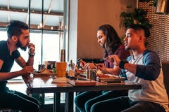Οι πολυφυλετικοί φίλοι τρώνε το πρόγευμα στον καφέ Οι νεαροί άνδρες κουβεντιάζουν ενώ έχοντας τα νόστιμα τρόφιμα και τα ποτά Πολυ στοκ εικόνες Οι πολυφυλετικοί φίλοι τρώνε το πρόγευμα στον καφέ Οι νεαροί άνδρες κουβεντιάζουν ενώ έχοντας τα νόστιμα τρόφιμα και τα ποτά Πολυ στοκ εικόνες
