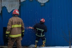 Οι πυροσβέστες εργάζονται σε μια πυρκαγιά της οικοδόμησης χρησιμοποιώντας ένα εργαλείο διάσωσης κοπτών μετάλλων κατά τη διάρκεια Στοκ Εικόνες Οι πυροσβέστες εργάζονται σε μια πυρκαγιά της οικοδόμησης χρησιμοποιώντας ένα εργαλείο διάσωσης κοπτών μετάλλων κατά τη διάρκεια Στοκ Εικόνες