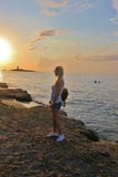 Οι στάσεις κοριτσιών στην ακτή και εξετάζουν το όμορφο ηλιοβασίλεμα στοκ εικόνες με δικαίωμα ελεύθερης χρήσης Οι στάσεις κοριτσιών στην ακτή και εξετάζουν το όμορφο ηλιοβασίλεμα στοκ εικόνες με δικαίωμα ελεύθερης χρήσης