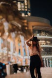 Οι όμορφες γυναίκες στα μοντέρνα ενδύματα καπέλων, βάναυσος άνδρας, μοντέρνη εξάρτηση, περπατούν κάτω από την οδό δροσερό φως και στοκ εικόνα με δικαίωμα ελεύθερης χρήσης Οι όμορφες γυναίκες στα μοντέρνα ενδύματα καπέλων, βάναυσος άνδρας, μοντέρνη εξάρτηση, περπατούν κάτω από την οδό δροσερό φως και στοκ εικόνα με δικαίωμα ελεύθερης χρήσης