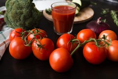 Οι ώριμες κόκκινες ντομάτες βρίσκονται σε έναν μαύρο μοντέρνο πίνακα στο υπόβαθρο βλέπουμε ένα ποτήρι του χυμού ντοματών, κόκκινα στοκ εικόνες με δικαίωμα ελεύθερης χρήσης Οι ώριμες κόκκινες ντομάτες βρίσκονται σε έναν μαύρο μοντέρνο πίνακα στο υπόβαθρο βλέπουμε ένα ποτήρι του χυμού ντοματών, κόκκινα στοκ εικόνες με δικαίωμα ελεύθερης χρήσης