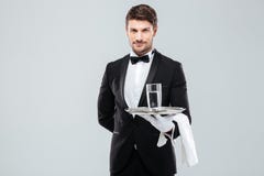 Οικονόμος στα γάντια που κρατά το ποτήρι του νερού στον ασημένιο δίσκο στοκ φωτογραφία με δικαίωμα ελεύθερης χρήσης Οικονόμος στα γάντια που κρατά το ποτήρι του νερού στον ασημένιο δίσκο στοκ φωτογραφία με δικαίωμα ελεύθερης χρήσης