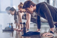 Ομάδα αθλητικών νέων sportswear που κάνει την ώθηση UPS ή τη σανίδα στη γυμναστική στοκ εικόνες Ομάδα αθλητικών νέων sportswear που κάνει την ώθηση UPS ή τη σανίδα στη γυμναστική στοκ εικόνες