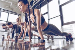 Ομάδα αθλητικών νέων sportswear που κάνει την ώθηση UPS ή τη σανίδα στη γυμναστική στοκ φωτογραφία Ομάδα αθλητικών νέων sportswear που κάνει την ώθηση UPS ή τη σανίδα στη γυμναστική στοκ φωτογραφία