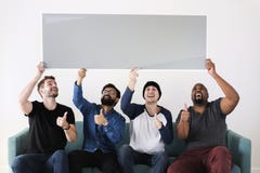 Ομάδα διαφορετικών φίλων που κάθονται στον καναπέ που κρατά τον κενό πίνακα στοκ εικόνα με δικαίωμα ελεύθερης χρήσης Ομάδα διαφορετικών φίλων που κάθονται στον καναπέ που κρατά τον κενό πίνακα στοκ εικόνα με δικαίωμα ελεύθερης χρήσης