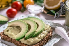 Οργανικό αβοκάντο Guacamole που διαδίδονται και φέτες με τη φρέσκια ντομάτα κερασιών και το μαύρο σουσάμι Υγιής έννοια προγευμάτω στοκ εικόνα με δικαίωμα ελεύθερης χρήσης Οργανικό αβοκάντο Guacamole που διαδίδονται και φέτες με τη φρέσκια ντομάτα κερασιών και το μαύρο σουσάμι Υγιής έννοια προγευμάτω στοκ εικόνα με δικαίωμα ελεύθερης χρήσης