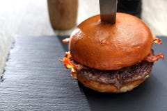 Ορεκτικό burger με το βόειο κρέας και το τηγανισμένο μπέϊκον στοκ εικόνα Ορεκτικό burger με το βόειο κρέας και το τηγανισμένο μπέϊκον στοκ εικόνα