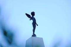 Ουρανός σκιαγραφιών με ένα άγαλμα cupid που στέκεται σε έναν άσπρο πόλο τσιμέντου με το υπόβαθρο μπλε ουρανού στοκ εικόνες με δικαίωμα ελεύθερης χρήσης Ουρανός σκιαγραφιών με ένα άγαλμα cupid που στέκεται σε έναν άσπρο πόλο τσιμέντου με το υπόβαθρο μπλε ουρανού στοκ εικόνες με δικαίωμα ελεύθερης χρήσης