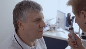 Οφθαλμολόγος cheks τα μάτια του ενήλικου ατόμου με το λαμπτήρα φιλμ μικρού μήκους Οφθαλμολόγος cheks τα μάτια του ενήλικου ατόμου με το λαμπτήρα φιλμ μικρού μήκους