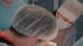 Πλαστικοί χειρούργοι που ολοκληρώνουν τη λειτουργία με το χρησιμοποιώντας αποστειρωμένο εξοπλισμό ραψίματος φιλμ μικρού μήκους Πλαστικοί χειρούργοι που ολοκληρώνουν τη λειτουργία με το χρησιμοποιώντας αποστειρωμένο εξοπλισμό ραψίματος φιλμ μικρού μήκους