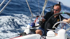 Πλοίαρχος στους ελέγχους τιμονιών ενός πλέοντας γιοτ κατά τη διάρκεια της φυλής Πλοίαρχος στους ελέγχους τιμονιών ενός πλέοντας γιοτ κατά τη διάρκεια της φυλής