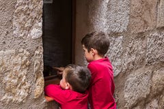 Παιδιά που κοιτάζουν από ένα παράθυρο ενός σπιτιού στην οδό στοκ φωτογραφία Παιδιά που κοιτάζουν από ένα παράθυρο ενός σπιτιού στην οδό στοκ φωτογραφία