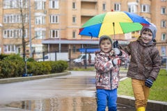 Παιχνίδι μικρών παιδιών στο βροχερό θερινό πάρκο Το παιδί με τη ζωηρόχρωμη ομπρέλα ουράνιων τόξων, στεγανοποιεί το παλτό και τις Στοκ εικόνες με δικαίωμα ελεύθερης χρήσης Παιχνίδι μικρών παιδιών στο βροχερό θερινό πάρκο Το παιδί με τη ζωηρόχρωμη ομπρέλα ουράνιων τόξων, στεγανοποιεί το παλτό και τις Στοκ εικόνες με δικαίωμα ελεύθερης χρήσης