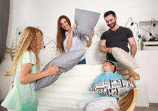 Παιχνίδι νέων οικογενειών και δύο παιδιών που παλεύει στο σπίτι με τα μαξιλάρια στοκ φωτογραφίες Παιχνίδι νέων οικογενειών και δύο παιδιών που παλεύει στο σπίτι με τα μαξιλάρια στοκ φωτογραφίες