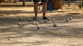 Παιχνίδι Petanque στο πάρκο - σφαίρες μετάλλων και πορτοκαλιά ξύλινη σφαίρα στο ναυπηγείο βράχου με ένα άτομο που στέκεται στον ή στοκ εικόνα με δικαίωμα ελεύθερης χρήσης Παιχνίδι Petanque στο πάρκο - σφαίρες μετάλλων και πορτοκαλιά ξύλινη σφαίρα στο ναυπηγείο βράχου με ένα άτομο που στέκεται στον ή στοκ εικόνα με δικαίωμα ελεύθερης χρήσης