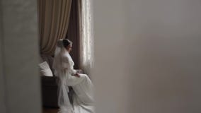 Πανέμορφη συνεδρίαση νυφών στην καρέκλα στο σπίτι Όμορφη γυναίκα στο γαμήλιο φόρεμα φιλμ μικρού μήκους Πανέμορφη συνεδρίαση νυφών στην καρέκλα στο σπίτι Όμορφη γυναίκα στο γαμήλιο φόρεμα φιλμ μικρού μήκους