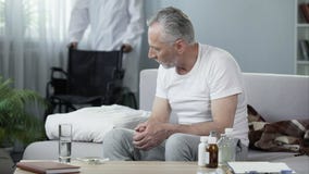 Παρεμποδισμένη συνεδρίαση ατόμων στον καναπέ στη ιδιωτική κλινική, αρσενική φέρνοντας αναπηρική καρέκλα νοσοκόμων Στοκ Εικόνα Παρεμποδισμένη συνεδρίαση ατόμων στον καναπέ στη ιδιωτική κλινική, αρσενική φέρνοντας αναπηρική καρέκλα νοσοκόμων Στοκ Εικόνα