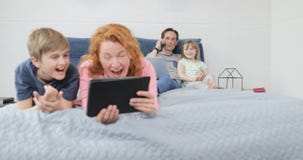 Πατέρας που αγκαλιάζει λίγη κόρη μιλώντας στο τηλεφώνημα την ευτυχή οικογενειακή συνεδρίαση χαμόγελου μαζί στο κρεβάτι απόθεμα βίντεο Πατέρας που αγκαλιάζει λίγη κόρη μιλώντας στο τηλεφώνημα την ευτυχή οικογενειακή συνεδρίαση χαμόγελου μαζί στο κρεβάτι απόθεμα βίντεο