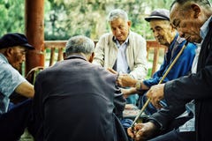 Πεκίνο/Κίνα - 24 Ιουνίου 2011: ηλικιωμένες κινεζικές κάρτες παιχνιδιού ατόμων σε ένα πάρκο ενώ ένας από τους που καπνίζουν ένα πο στοκ φωτογραφία με δικαίωμα ελεύθερης χρήσης Πεκίνο/Κίνα - 24 Ιουνίου 2011: ηλικιωμένες κινεζικές κάρτες παιχνιδιού ατόμων σε ένα πάρκο ενώ ένας από τους που καπνίζουν ένα πο στοκ φωτογραφία με δικαίωμα ελεύθερης χρήσης