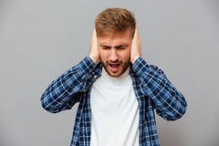 Περιστασιακό γενειοφόρο άτομο που καλύπτει τα αυτιά και να φωνάξει του Στοκ Εικόνες Περιστασιακό γενειοφόρο άτομο που καλύπτει τα αυτιά και να φωνάξει του Στοκ Εικόνες