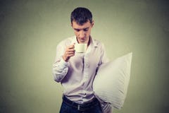 Πολύ κουρασμένο, μειωμένο κοιμισμένο επιχειρησιακό άτομο που κρατά ένα φλιτζάνι του καφέ και ένα μαξιλάρι στοκ φωτογραφία με δικαίωμα ελεύθερης χρήσης Πολύ κουρασμένο, μειωμένο κοιμισμένο επιχειρησιακό άτομο που κρατά ένα φλιτζάνι του καφέ και ένα μαξιλάρι στοκ φωτογραφία με δικαίωμα ελεύθερης χρήσης