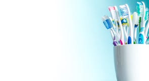 Πολύχρωμες οδοντόβουρτσες σε μια άσπρη κινηματογράφηση σε πρώτο πλάνο κουπών με ένα υπόβαθρο κλίσης από άσπρο στο μπλε με μια απο στοκ εικόνα Πολύχρωμες οδοντόβουρτσες σε μια άσπρη κινηματογράφηση σε πρώτο πλάνο κουπών με ένα υπόβαθρο κλίσης από άσπρο στο μπλε με μια απο στοκ εικόνα