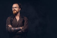 Πορτρέτο ενός redhead σπουδαστή hipster στα γυαλιά που ντύνονται σε ένα καφετί πουκάμισο, κρατά ένα σακίδιο πλάτης, που θέτει σε στοκ εικόνα Πορτρέτο ενός redhead σπουδαστή hipster στα γυαλιά που ντύνονται σε ένα καφετί πουκάμισο, κρατά ένα σακίδιο πλάτης, που θέτει σε στοκ εικόνα