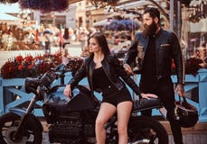 Πορτρέτο ενός ζεύγους hipster - νέα αισθησιακή συνεδρίαση κοριτσιών στην επί παραγγελία αναδρομική μοτοσικλέτα του και ένα γενειο στοκ εικόνα με δικαίωμα ελεύθερης χρήσης Πορτρέτο ενός ζεύγους hipster - νέα αισθησιακή συνεδρίαση κοριτσιών στην επί παραγγελία αναδρομική μοτοσικλέτα του και ένα γενειο στοκ εικόνα με δικαίωμα ελεύθερης χρήσης
