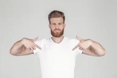 Πορτρέτο ενός όμορφου προκλητικού hipster που ντύνεται σε μια άσπρη μπλούζα Παρουσιάζει χέρια στην μπλούζα του θέση για το λογότυ στοκ εικόνες Πορτρέτο ενός όμορφου προκλητικού hipster που ντύνεται σε μια άσπρη μπλούζα Παρουσιάζει χέρια στην μπλούζα του θέση για το λογότυ στοκ εικόνες