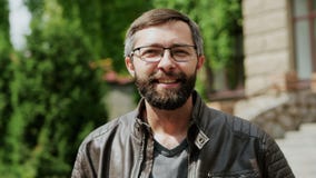 Πορτρέτο κινηματογραφήσεων σε πρώτο πλάνο του ελκυστικού γενειοφόρου ατόμου που εξετάζει τη κάμερα και το χαμόγελο φιλμ μικρού μήκους Πορτρέτο κινηματογραφήσεων σε πρώτο πλάνο του ελκυστικού γενειοφόρου ατόμου που εξετάζει τη κάμερα και το χαμόγελο φιλμ μικρού μήκους