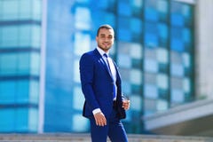 Πορτρέτο του βέβαιου εύθυμου επιχειρηματία στην μπλε στάση κοστουμιών στοκ εικόνα με δικαίωμα ελεύθερης χρήσης Πορτρέτο του βέβαιου εύθυμου επιχειρηματία στην μπλε στάση κοστουμιών στοκ εικόνα με δικαίωμα ελεύθερης χρήσης
