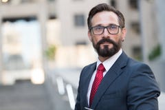 Πορτρέτο του γενειοφόρου ατόμου στο κοστούμι στο υπόβαθρο της οικοδόμησης Όμορφος επιχειρηματίας υπαίθριος Αρσενικές στάσεις επιχ στοκ φωτογραφία με δικαίωμα ελεύθερης χρήσης Πορτρέτο του γενειοφόρου ατόμου στο κοστούμι στο υπόβαθρο της οικοδόμησης Όμορφος επιχειρηματίας υπαίθριος Αρσενικές στάσεις επιχ στοκ φωτογραφία με δικαίωμα ελεύθερης χρήσης