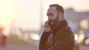 Πορτρέτο του δημιουργικού νέου γενειοφόρου αρσενικού που έχει τη διασκέδαση που χαμογελά και που μιλά χρησιμοποιώντας το smartpho φιλμ μικρού μήκους Πορτρέτο του δημιουργικού νέου γενειοφόρου αρσενικού που έχει τη διασκέδαση που χαμογελά και που μιλά χρησιμοποιώντας το smartpho φιλμ μικρού μήκους