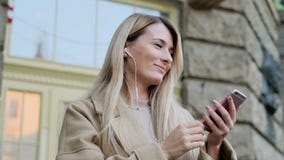 Πορτρέτο του χαριτωμένου κοριτσιού στα ακουστικά, που ακούει τη μουσική και που κοιτάζει βιαστικά στο κινητό τηλεφωνικό outddor Κ απόθεμα βίντεο Πορτρέτο του χαριτωμένου κοριτσιού στα ακουστικά, που ακούει τη μουσική και που κοιτάζει βιαστικά στο κινητό τηλεφωνικό outddor Κ απόθεμα βίντεο