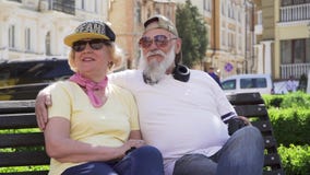 Πορτρέτο του χαρωπού μοντέρνου ηλικιωμένου ανθρώπου που χαλαρώνει στον πάγκο στην πόλη φιλμ μικρού μήκους Πορτρέτο του χαρωπού μοντέρνου ηλικιωμένου ανθρώπου που χαλαρώνει στον πάγκο στην πόλη φιλμ μικρού μήκους