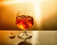 Ποτήρι του ουίσκυ με τις πτώσεις και του πάγου σε ένα πορτοκαλί υπόβαθρο στοκ φωτογραφία Ποτήρι του ουίσκυ με τις πτώσεις και του πάγου σε ένα πορτοκαλί υπόβαθρο στοκ φωτογραφία