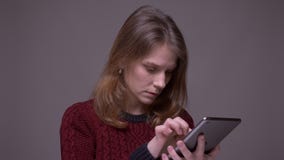Προσεκτική νέα προσοχή γυναικών σπουδαστών σοβαρά στην ταμπλέτα που συγκεντρώνεται στο γκρίζο υπόβαθρο φιλμ μικρού μήκους Προσεκτική νέα προσοχή γυναικών σπουδαστών σοβαρά στην ταμπλέτα που συγκεντρώνεται στο γκρίζο υπόβαθρο φιλμ μικρού μήκους