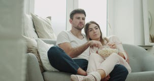 Πρωί μαζί για ένα ζεύγος που TV προσοχής και κατανάλωση popcorn στις πυτζάμες που κάθονται στο άνετο ύφος καναπέδων απόθεμα βίντεο Πρωί μαζί για ένα ζεύγος που TV προσοχής και κατανάλωση popcorn στις πυτζάμες που κάθονται στο άνετο ύφος καναπέδων απόθεμα βίντεο