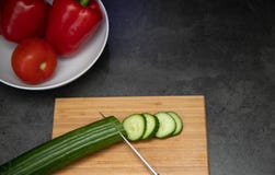 Πρόσφατα τεμαχισμένα αγγούρια με το μαχαίρι στον ξύλινο τέμνοντα πίνακα με ένα πιάτο της πάπρικας και της ντομάτας στοκ εικόνες Πρόσφατα τεμαχισμένα αγγούρια με το μαχαίρι στον ξύλινο τέμνοντα πίνακα με ένα πιάτο της πάπρικας και της ντομάτας στοκ εικόνες